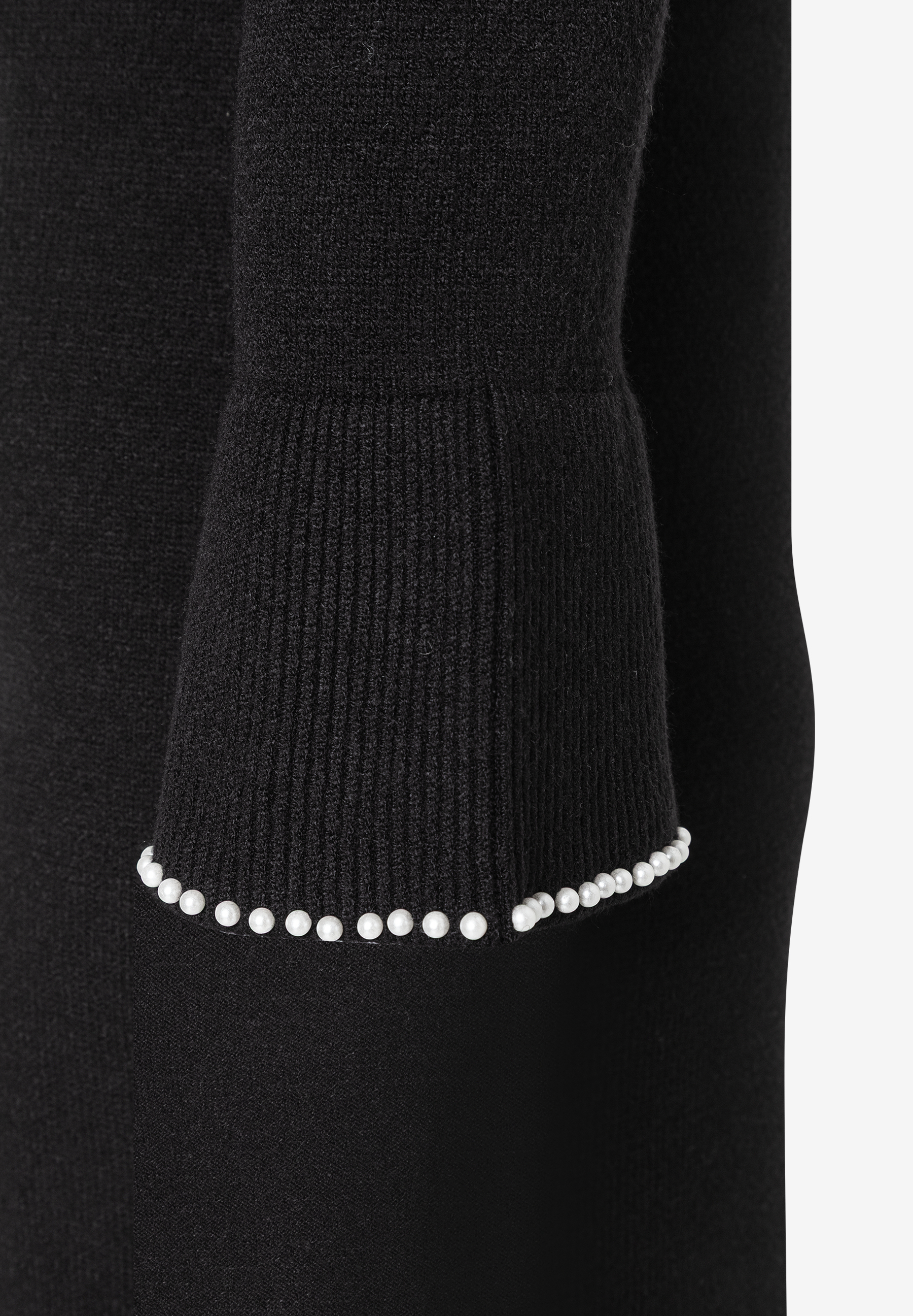 Ärmel eines schwarzen Strick-Oberteils von MORE & MORE mit Perlensaum. Ärmel eines schwarzen Strick-Oberteils von MORE & MORE mit Perlensaum.