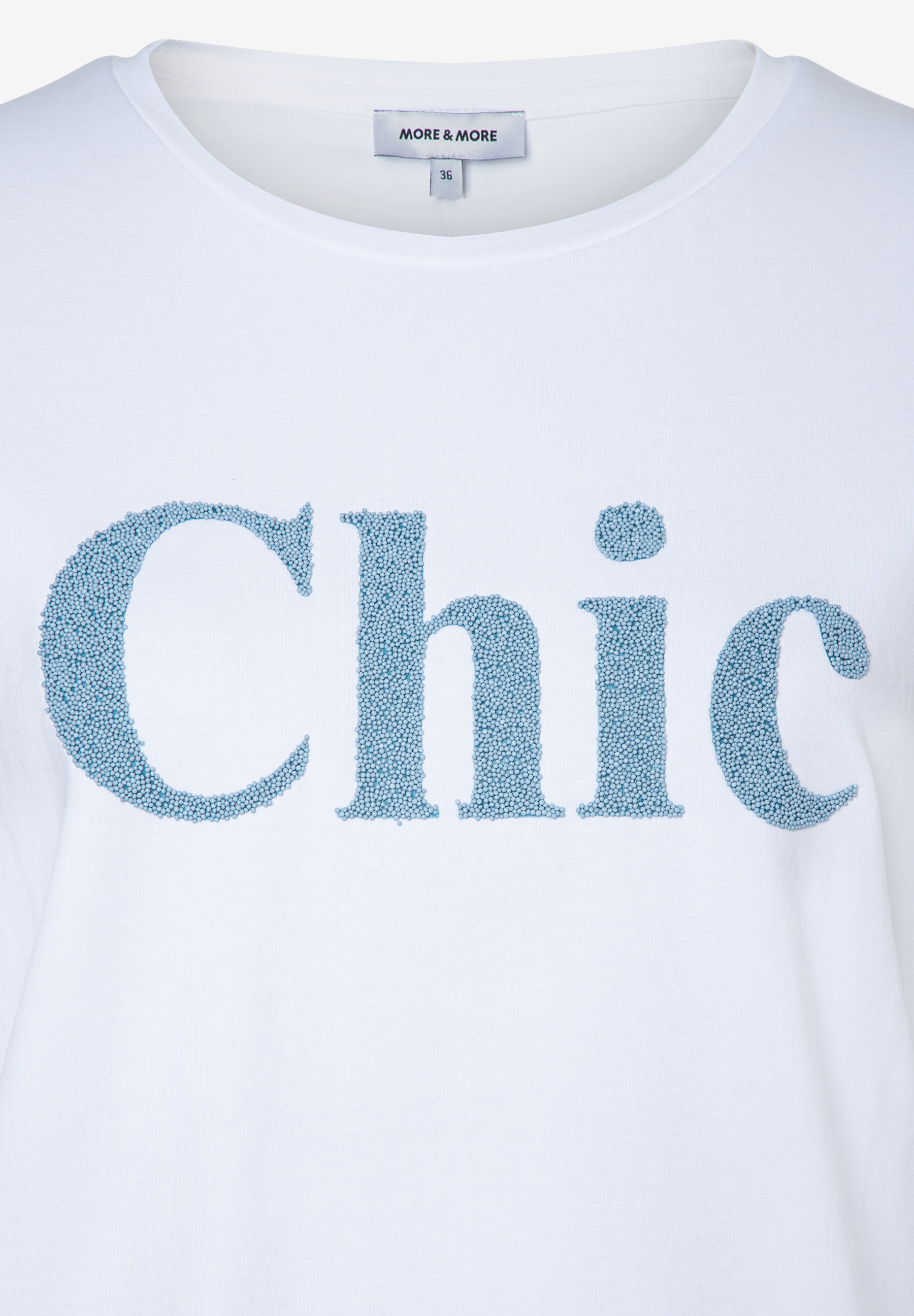 Ein weißes MORE & MORE T-Shirt mit blauem "Chic"-Schriftzug aus kleinen Kugeln. Ein weißes MORE & MORE T-Shirt mit blauem "Chic"-Schriftzug aus kleinen Kugeln.