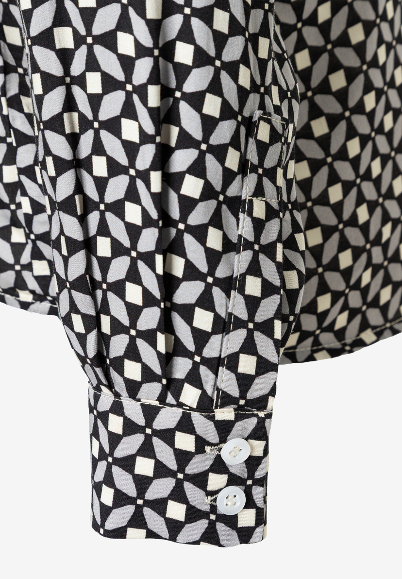Detailaufnahme einer MORE & MORE Bluse mit geometrischem Muster, Manschette und zwei Knöpfen. Detailaufnahme einer MORE & MORE Bluse mit geometrischem Muster, Manschette und zwei Knöpfen.
