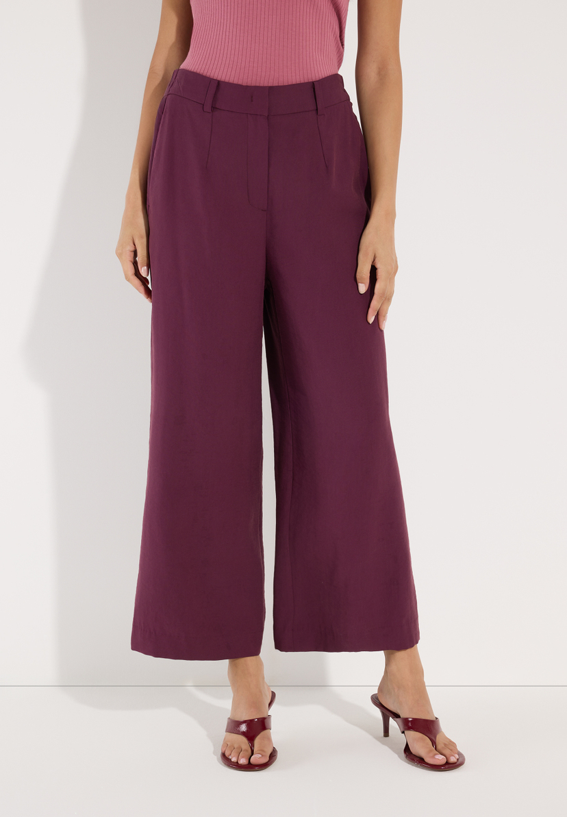 MORE & MORE Damen Jeans/Hose in Pflaume, kombiniert mit pinkem Oberteil und pflaumenfarbenen Mules mit Absatz.
