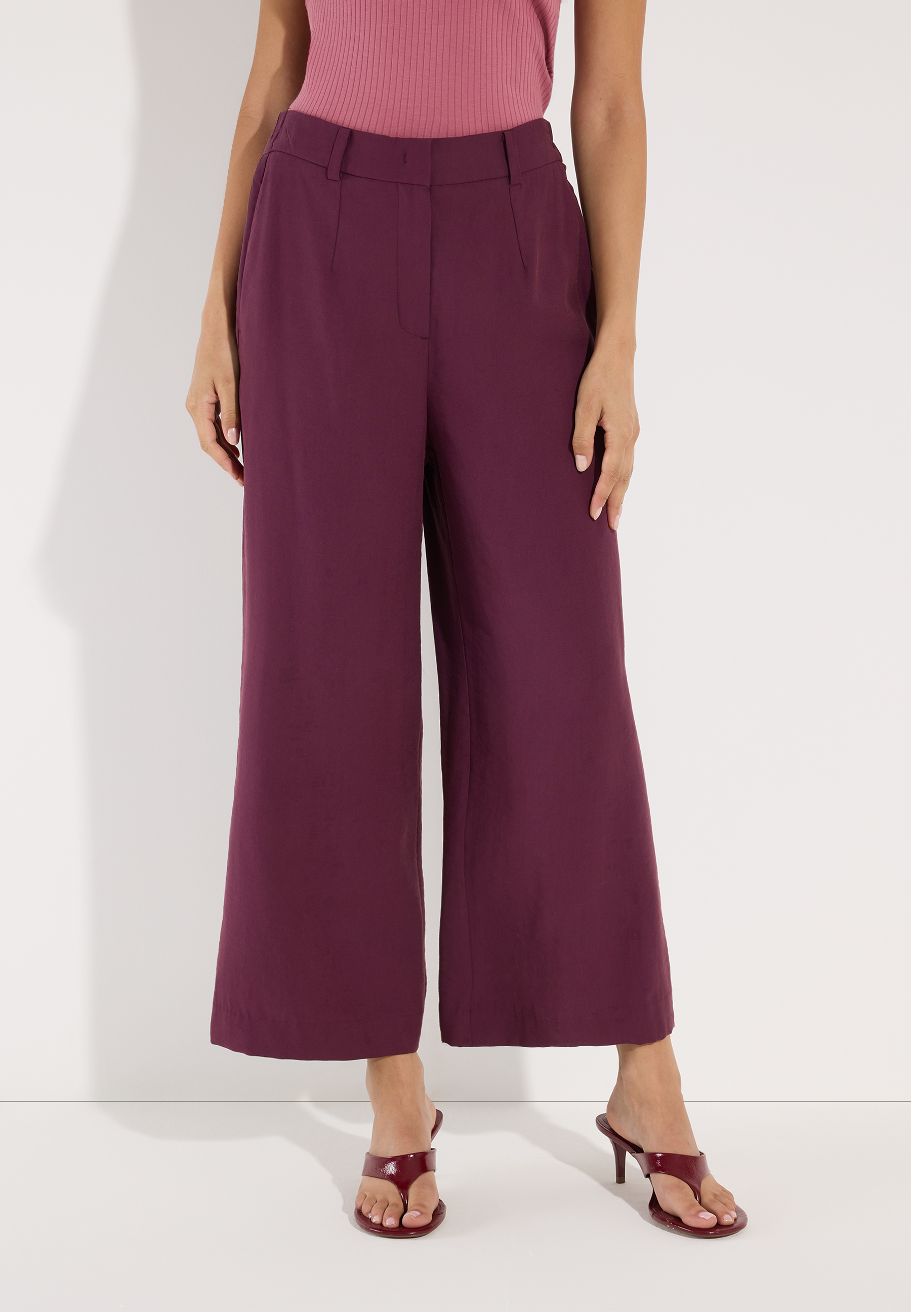 MORE & MORE Damen Jeans/Hose in Pflaume, kombiniert mit pinkem Oberteil und pflaumenfarbenen Mules mit Absatz.